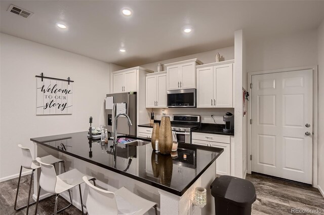21538 E 59th Pl, Aurora, CO 80019 - kitchen with a sink, a breakfast bar, visible vents, white cabinets, and appliances with stainless steel finishes