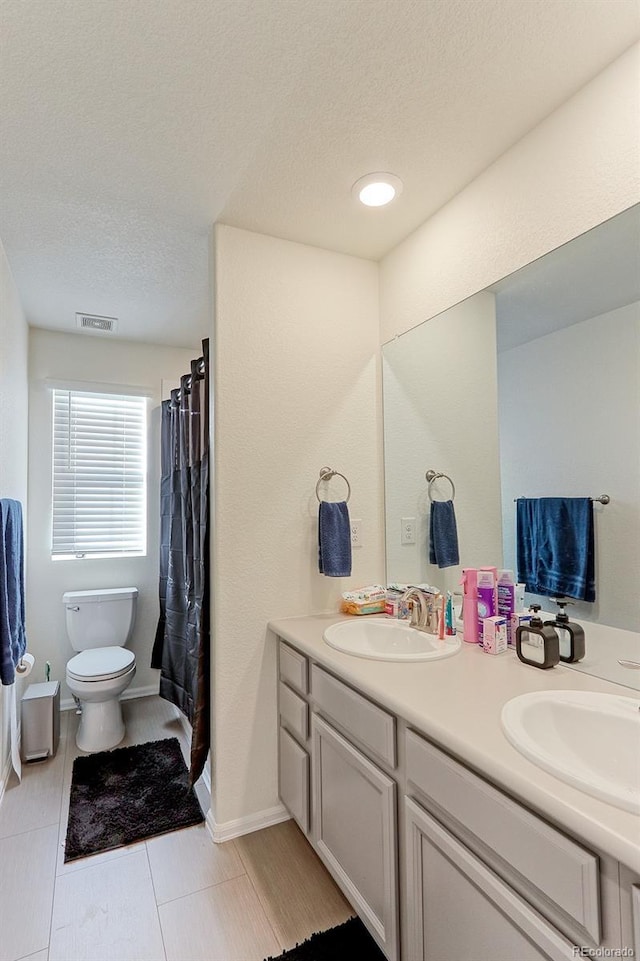 9448 Richfield St, Commerce City, CO 80022 - bathroom featuring double vanity, a textured ceiling, and toilet