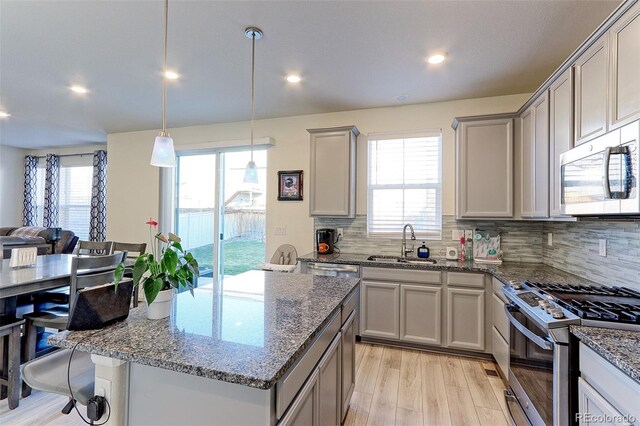 9448 Richfield St, Commerce City, CO 80022 - kitchen with stainless steel appliances, a sink, light wood-style floors, open floor plan, and tasteful backsplash