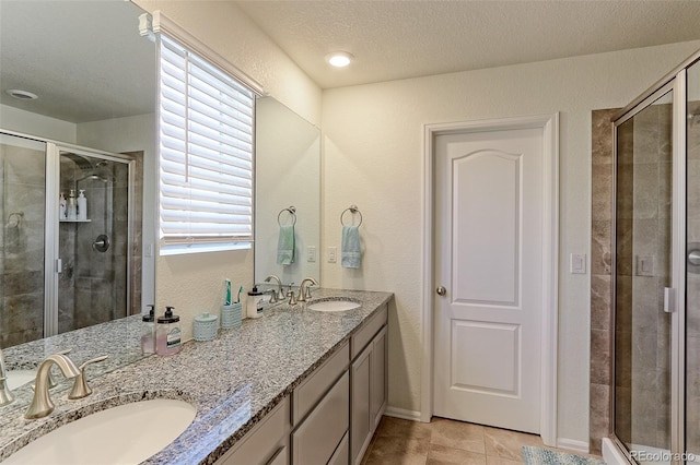 9448 Richfield St, Commerce City, CO 80022 - bathroom with a stall shower, double vanity, a textured ceiling, and tile patterned floors