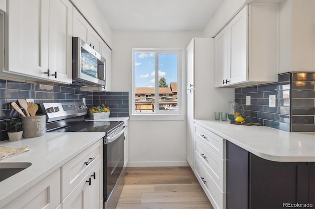 3855 S Monaco St Unit 182, Denver, CO 80237 - kitchen featuring appliances with stainless steel finishes, baseboards, light wood-style flooring, and white cabinetry