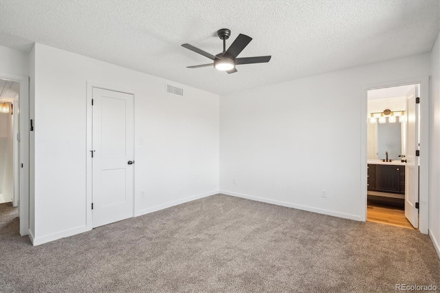 3855 S Monaco St Unit 182, Denver, CO 80237 - unfurnished bedroom featuring carpet flooring, a textured ceiling, a sink, ensuite bathroom, and baseboards