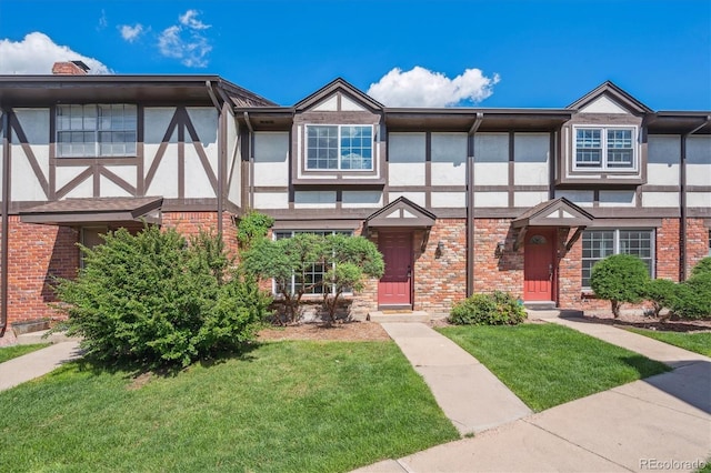 3855 S Monaco St Unit 182, Denver, CO 80237 - view of front of home with stucco siding, a front yard, brick siding, and a chimney