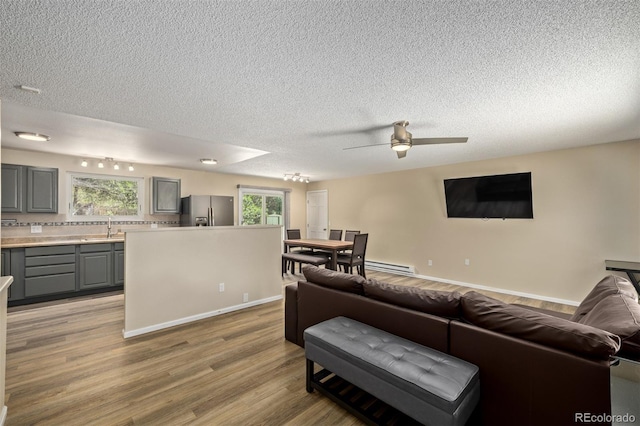 1394 S Zeno St, Aurora, CO 80017 - living area featuring a baseboard radiator, light wood-type flooring, a textured ceiling, and ceiling fan