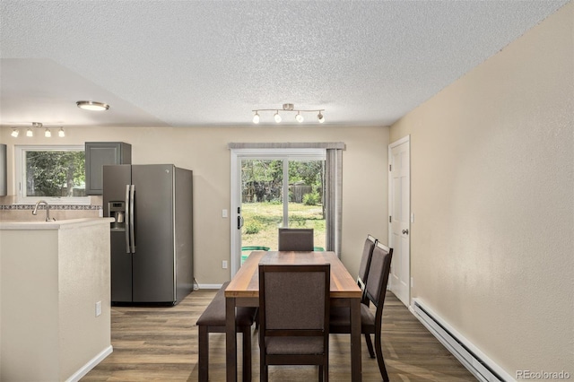 1394 S Zeno St, Aurora, CO 80017 - dining room featuring a baseboard radiator, wood finished floors, a textured ceiling, and rail lighting
