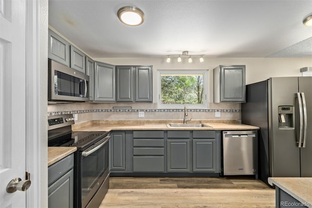 1394 S Zeno St, Aurora, CO 80017 - kitchen featuring stainless steel appliances, gray cabinets, tasteful backsplash, light countertops, and light wood finished floors