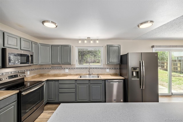 1394 S Zeno St, Aurora, CO 80017 - kitchen with appliances with stainless steel finishes, gray cabinetry, tasteful backsplash, light wood-style floors, and a textured ceiling