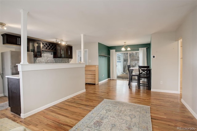 kitchen with tasteful backsplash, dark brown cabinetry, light hardwood / wood-style floors, and a notable chandelier