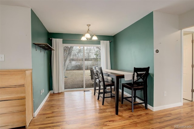 dining space featuring light wood-type flooring and an inviting chandelier