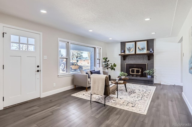 living room featuring a textured ceiling, a fireplace, and dark hardwood / wood-style floors