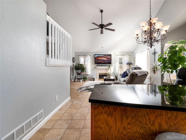 kitchen with lofted ceiling, decorative light fixtures, light tile patterned floors, a tile fireplace, and ceiling fan