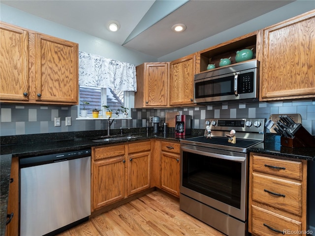 kitchen featuring appliances with stainless steel finishes, sink, decorative backsplash, and dark stone countertops