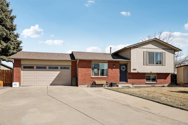 tri-level home with brick siding, driveway, an attached garage, and fence