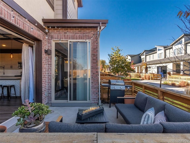 view of patio with grilling area, an outdoor living space with a fire pit, and a residential view