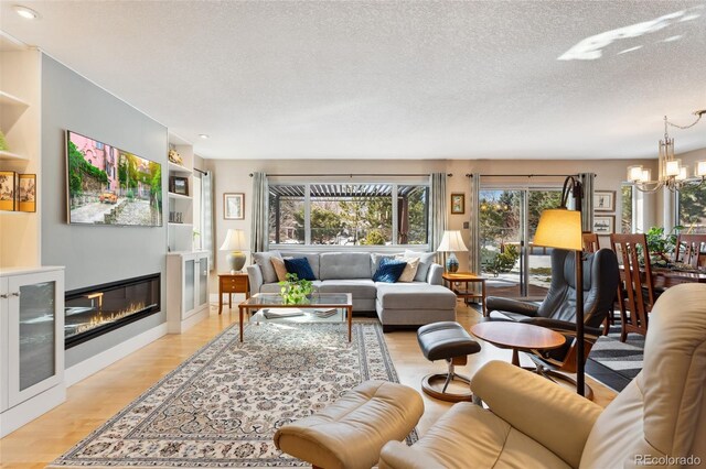 831 Crescent Dr, Boulder, CO 80303 - living area with a chandelier, light wood-type flooring, a textured ceiling, recessed lighting, and a glass covered fireplace
