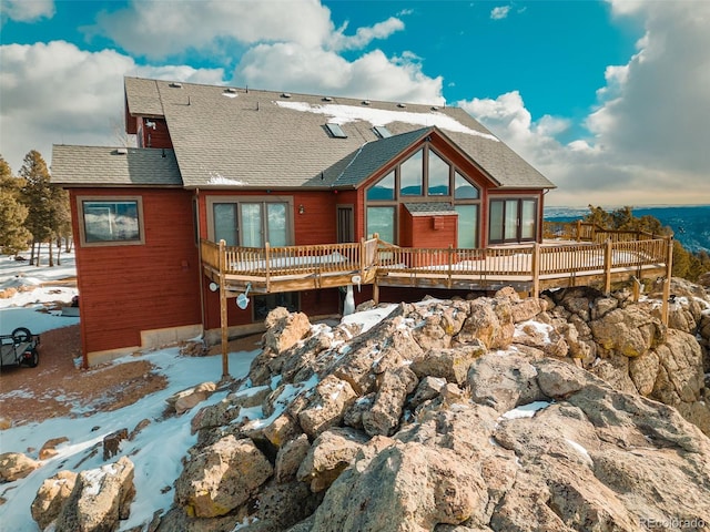 snow covered rear of property with a deck