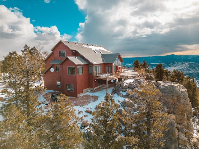 snow covered back of property featuring a deck with mountain view