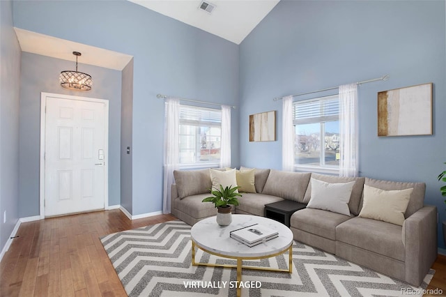 living room featuring high vaulted ceiling, wood-type flooring, and an inviting chandelier