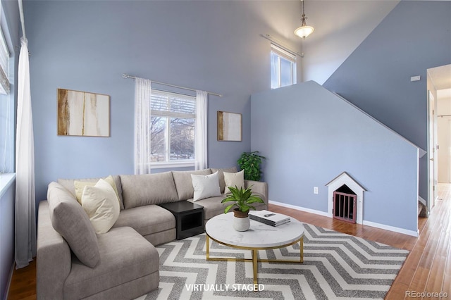 living room with a wealth of natural light, a towering ceiling, and hardwood / wood-style flooring