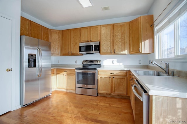 kitchen featuring appliances with stainless steel finishes, light hardwood / wood-style flooring, and sink