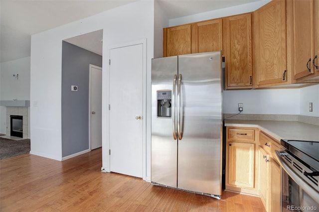 kitchen with a fireplace, stainless steel appliances, and light hardwood / wood-style floors