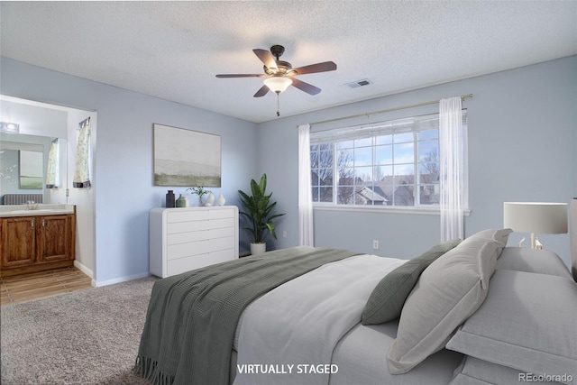 carpeted bedroom featuring ensuite bathroom, ceiling fan, sink, and a textured ceiling