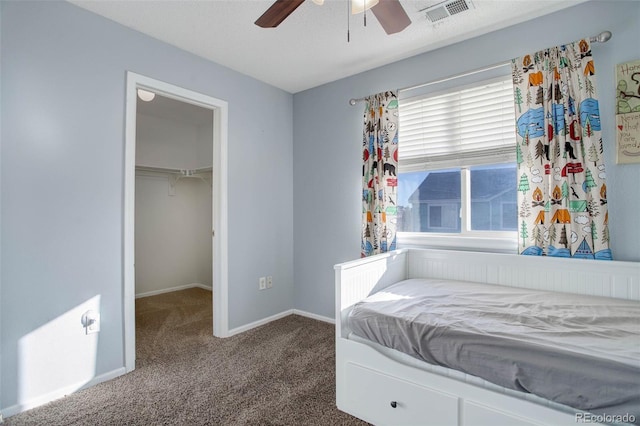 carpeted bedroom with ceiling fan, a walk in closet, and a closet