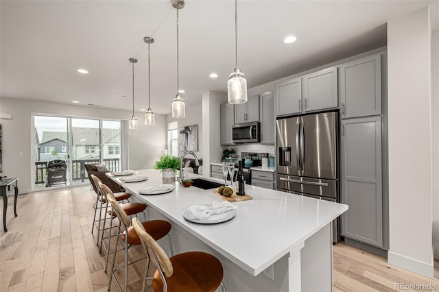 2052 Alcott Way, Broomfield, CO 80023 - kitchen featuring appliances with stainless steel finishes, gray cabinetry, a sink, a breakfast bar, and recessed lighting