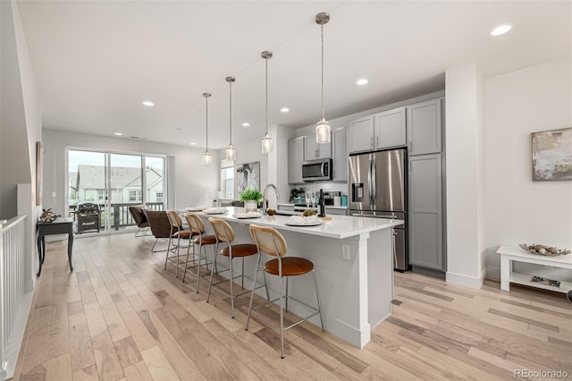 2052 Alcott Way, Broomfield, CO 80023 - kitchen with stainless steel appliances, gray cabinets, a kitchen bar, light wood-style floors, and light countertops