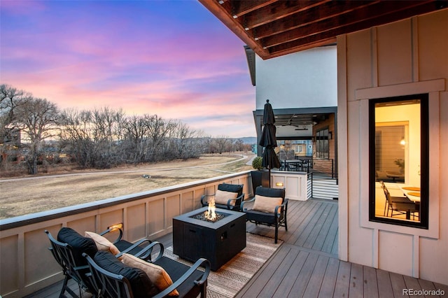 deck at dusk featuring a fire pit