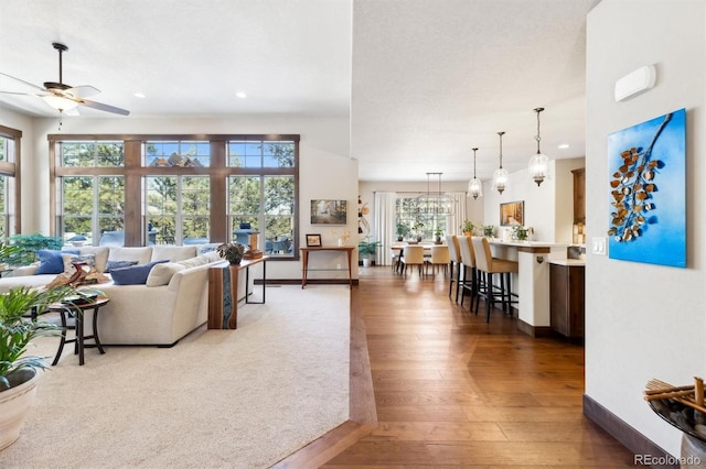 living room with ceiling fan with notable chandelier and hardwood / wood-style flooring