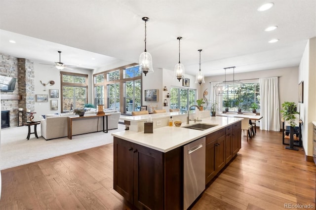 kitchen with light wood-type flooring, an island with sink, ceiling fan, sink, and stainless steel dishwasher