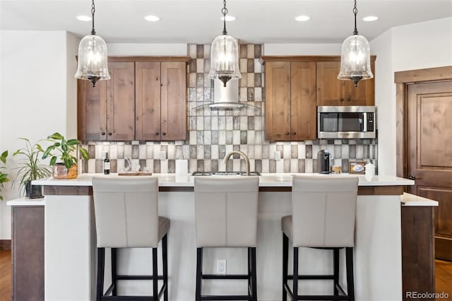 kitchen with backsplash, a breakfast bar, and hanging light fixtures