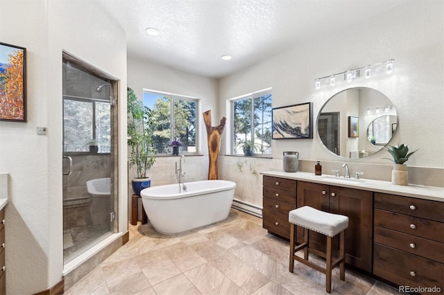 bathroom with a textured ceiling, separate shower and tub, vanity, and a baseboard heating unit