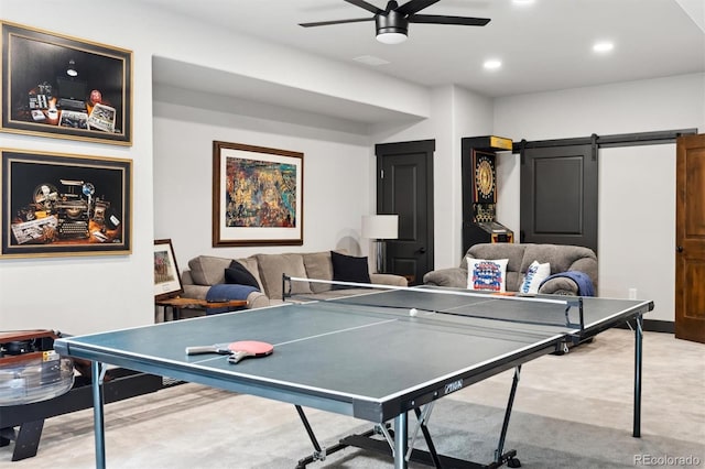 playroom featuring ceiling fan, a barn door, and light carpet