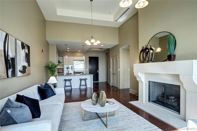 5455 Landmark Pl Unit 1403, Greenwood Village, CO 80111 - living room with a towering ceiling, dark wood-style floors, a fireplace with raised hearth, a raised ceiling, and a chandelier