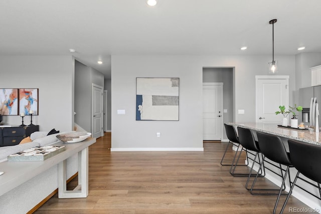 kitchen featuring recessed lighting, light wood-style flooring, light stone countertops, and stainless steel fridge with ice dispenser