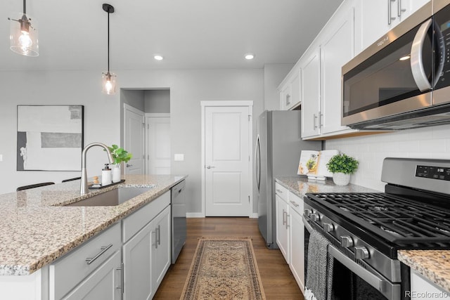 kitchen featuring dark wood-style flooring, a sink, appliances with stainless steel finishes, white cabinetry, and tasteful backsplash