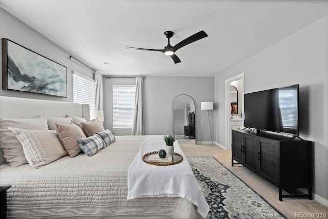 bedroom with light carpet, arched walkways, and baseboards