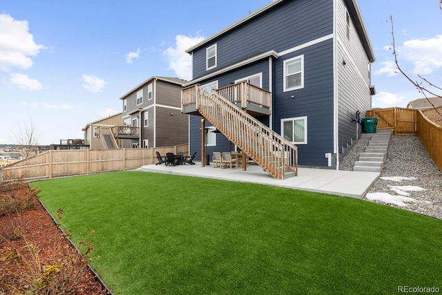 rear view of property featuring a lawn, a patio, a fenced backyard, stairway, and a wooden deck