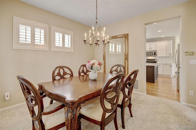 dining area featuring light carpet, a chandelier, visible vents, and baseboards
