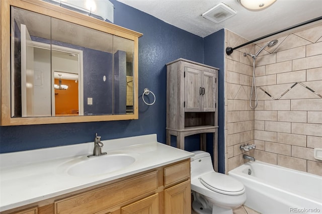 full bathroom with a textured ceiling, vanity, tiled shower / bath combo, and toilet