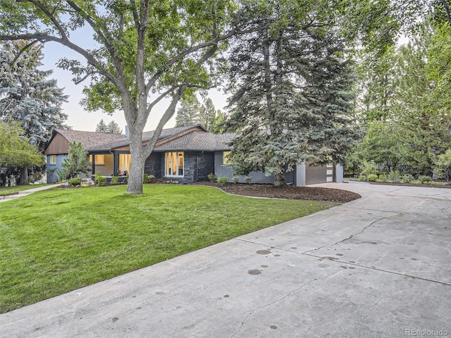 view of front of property featuring driveway, stone siding, a front lawn, and stucco siding