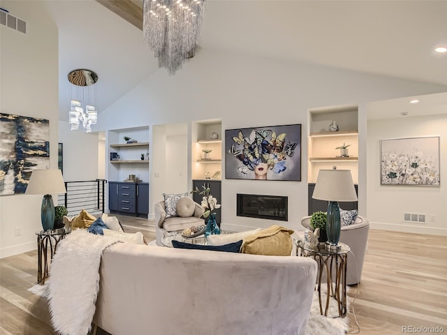 living room with a chandelier, high vaulted ceiling, baseboards, built in shelves, and light wood-type flooring
