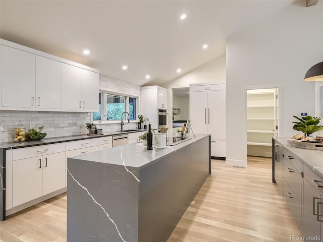 kitchen with stainless steel appliances, light wood finished floors, tasteful backsplash, a center island, and recessed lighting