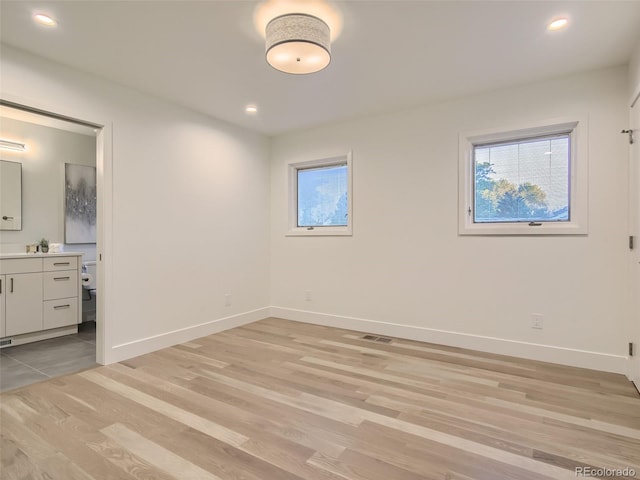 unfurnished bedroom featuring baseboards, light wood-style flooring, connected bathroom, and recessed lighting