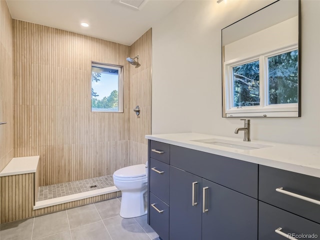 full bathroom featuring tile patterned flooring, tiled shower, toilet, and vanity