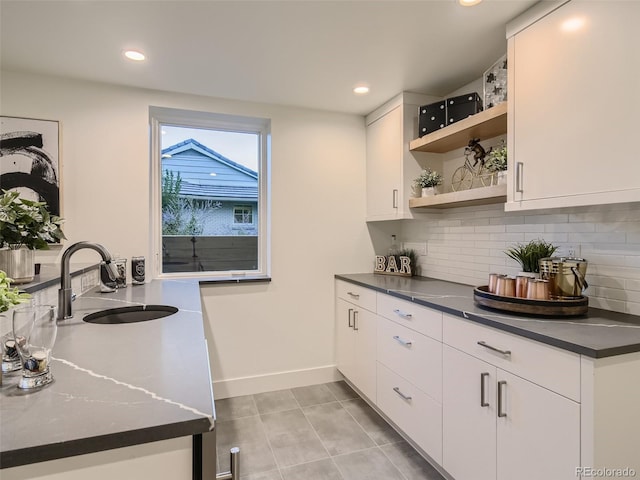 bar featuring a sink, decorative backsplash, recessed lighting, light tile patterned floors, and baseboards