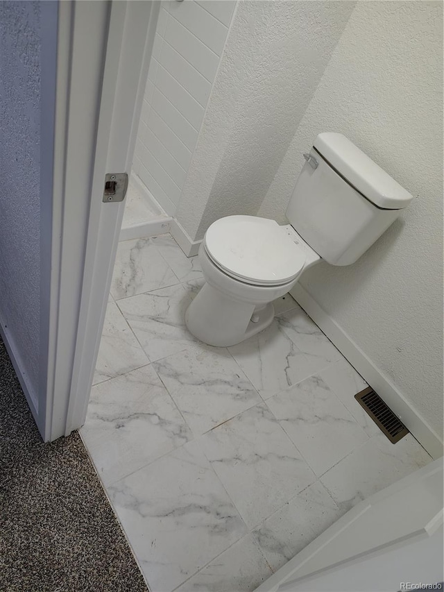 1045 Macdavidson Cir, Dacono, CO 80514 - bathroom featuring marble look tile flooring, toilet, baseboards, and a textured wall