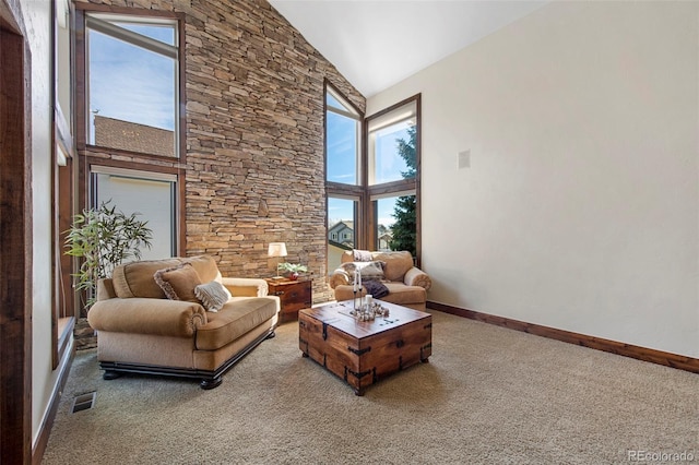 carpeted living area featuring baseboards, a healthy amount of sunlight, visible vents, and high vaulted ceiling